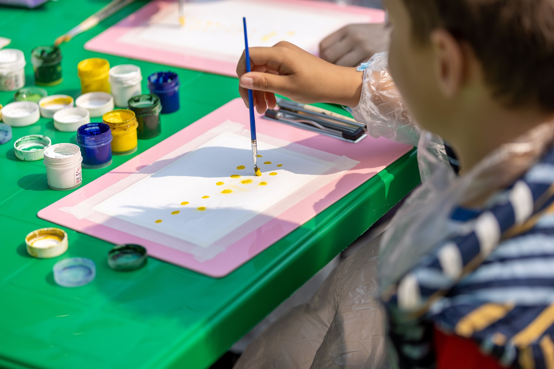 A child's hand working with colour on paper