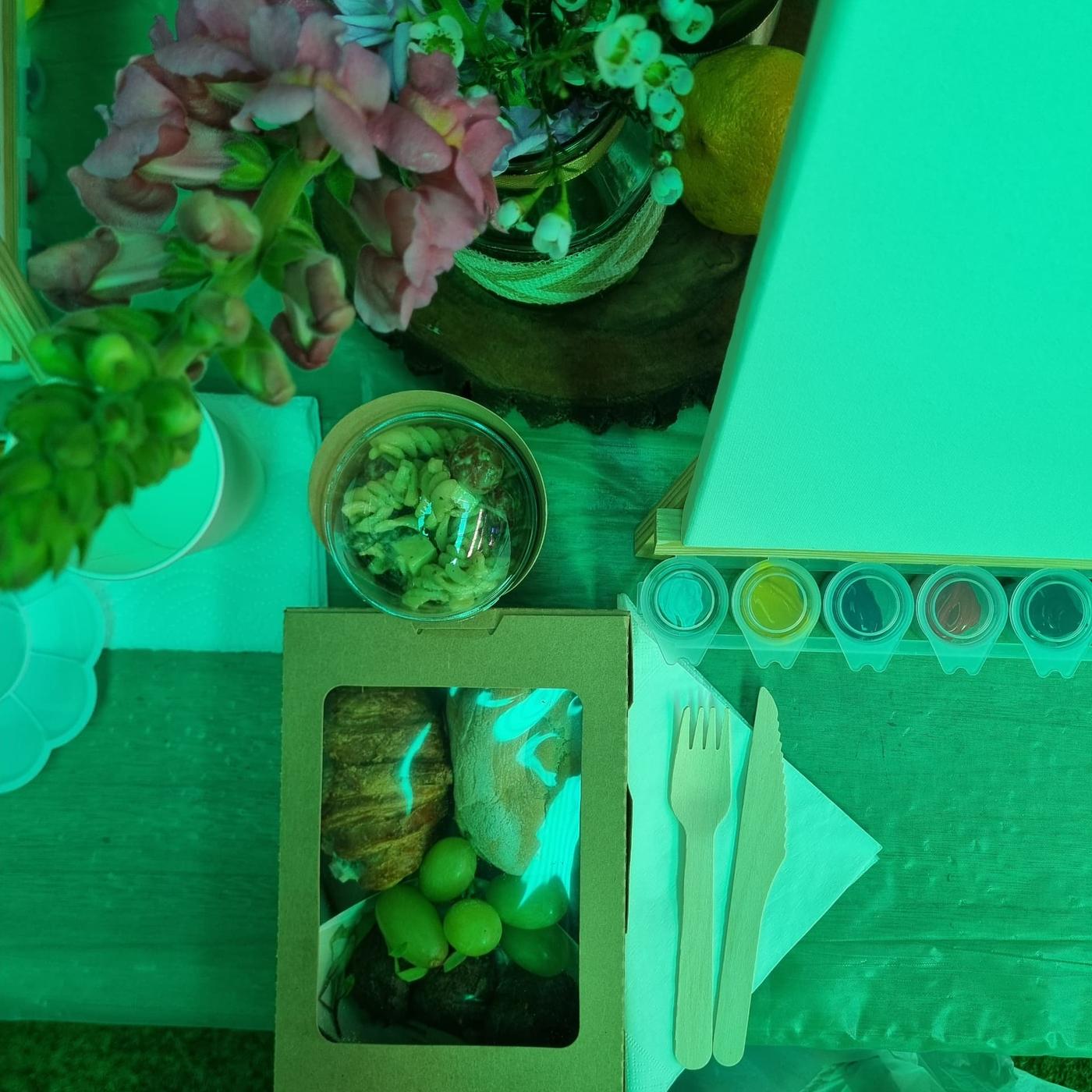 A guest's place setting with paint pots, brushes, a snack box and flowers at the Women's Day Sip & Paint