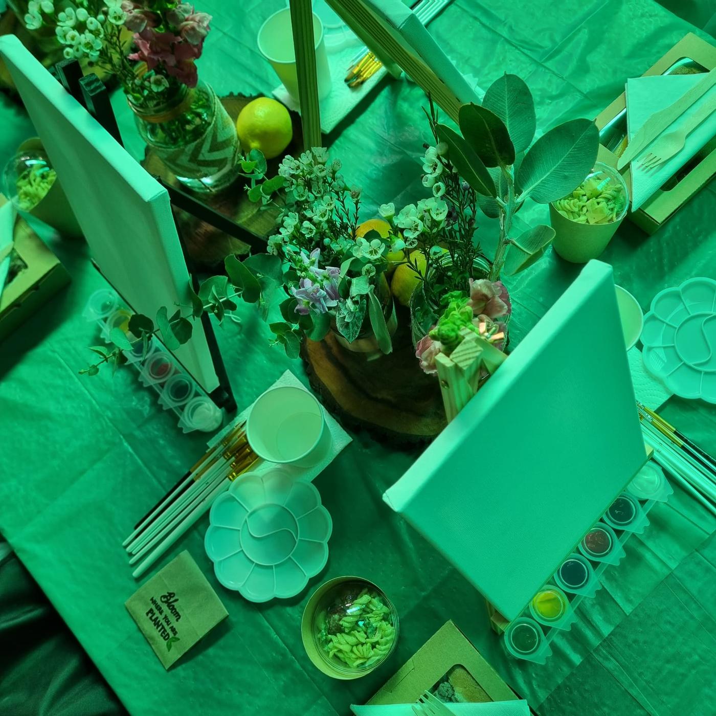 A styled garden-party table with palettes, brushes and fresh blooms ready for guests to paint