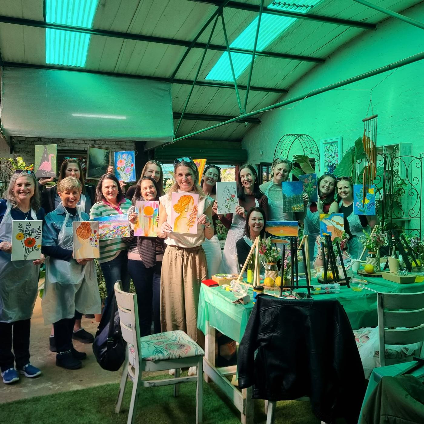 The Women's Day 2026 group proudly holding up their finished Strawberry Pot paintings