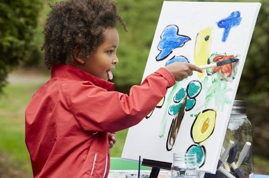 A little creator painting at an outdoor easel